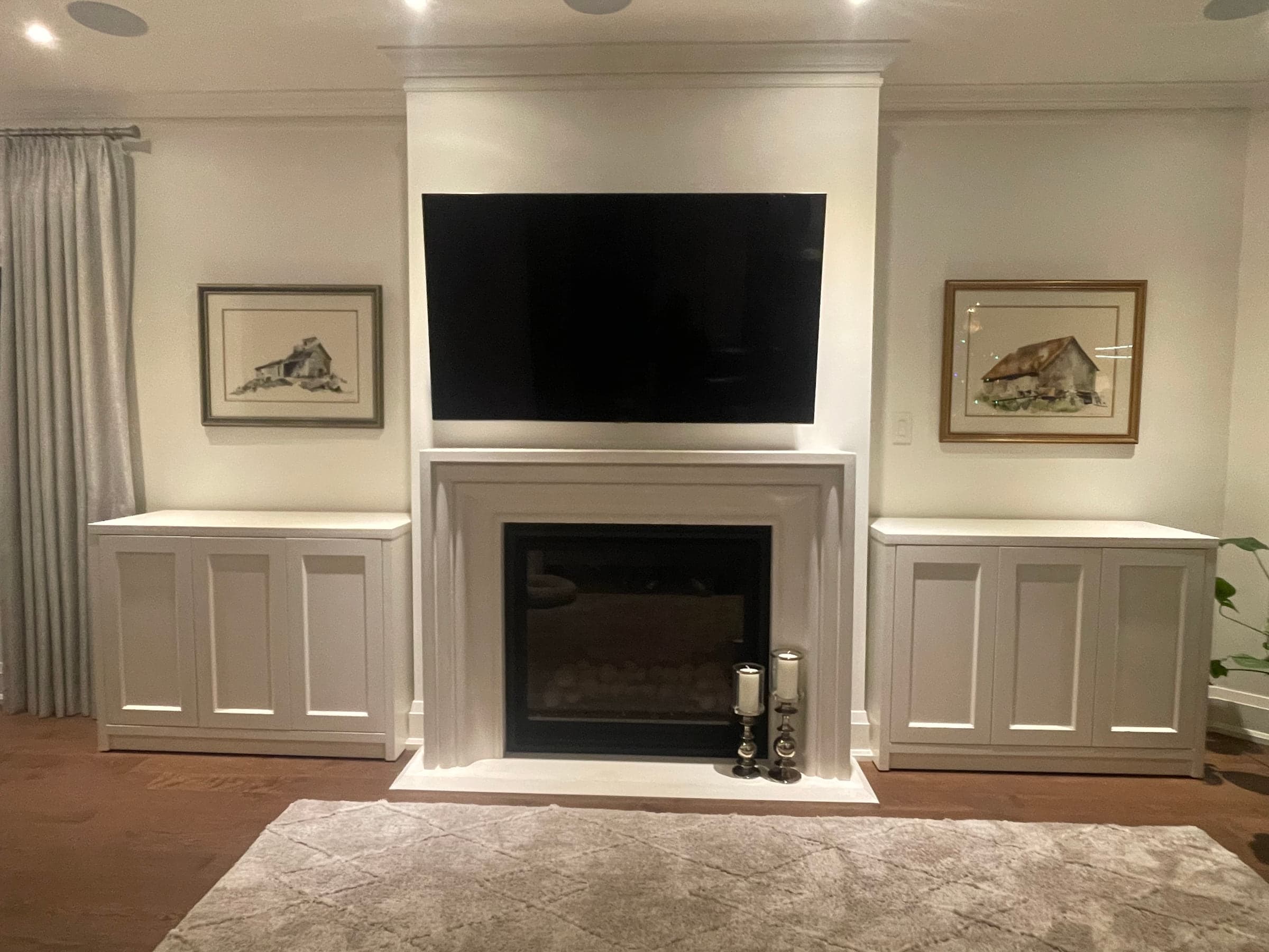 White built-in cabinetry arranged around a fireplace and television