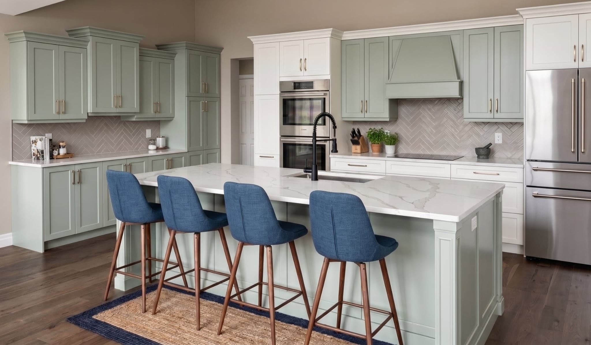 Wide white kitchen with a central island, pendant lights, and wood flooring