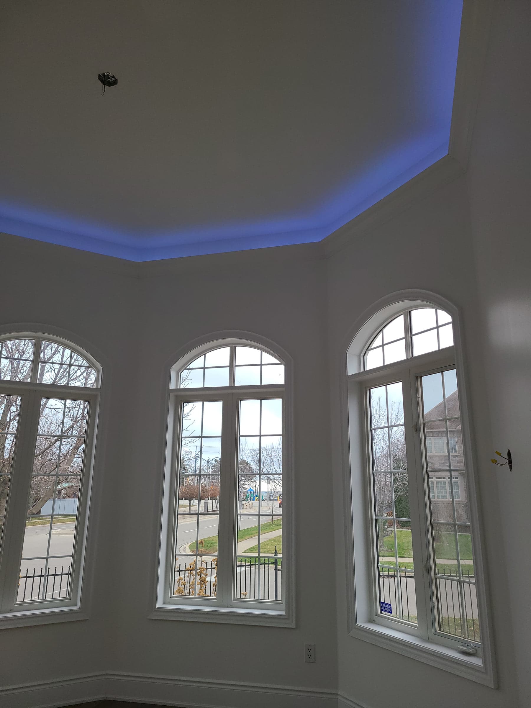 Three tall arched windows beneath a blue-lit tray ceiling