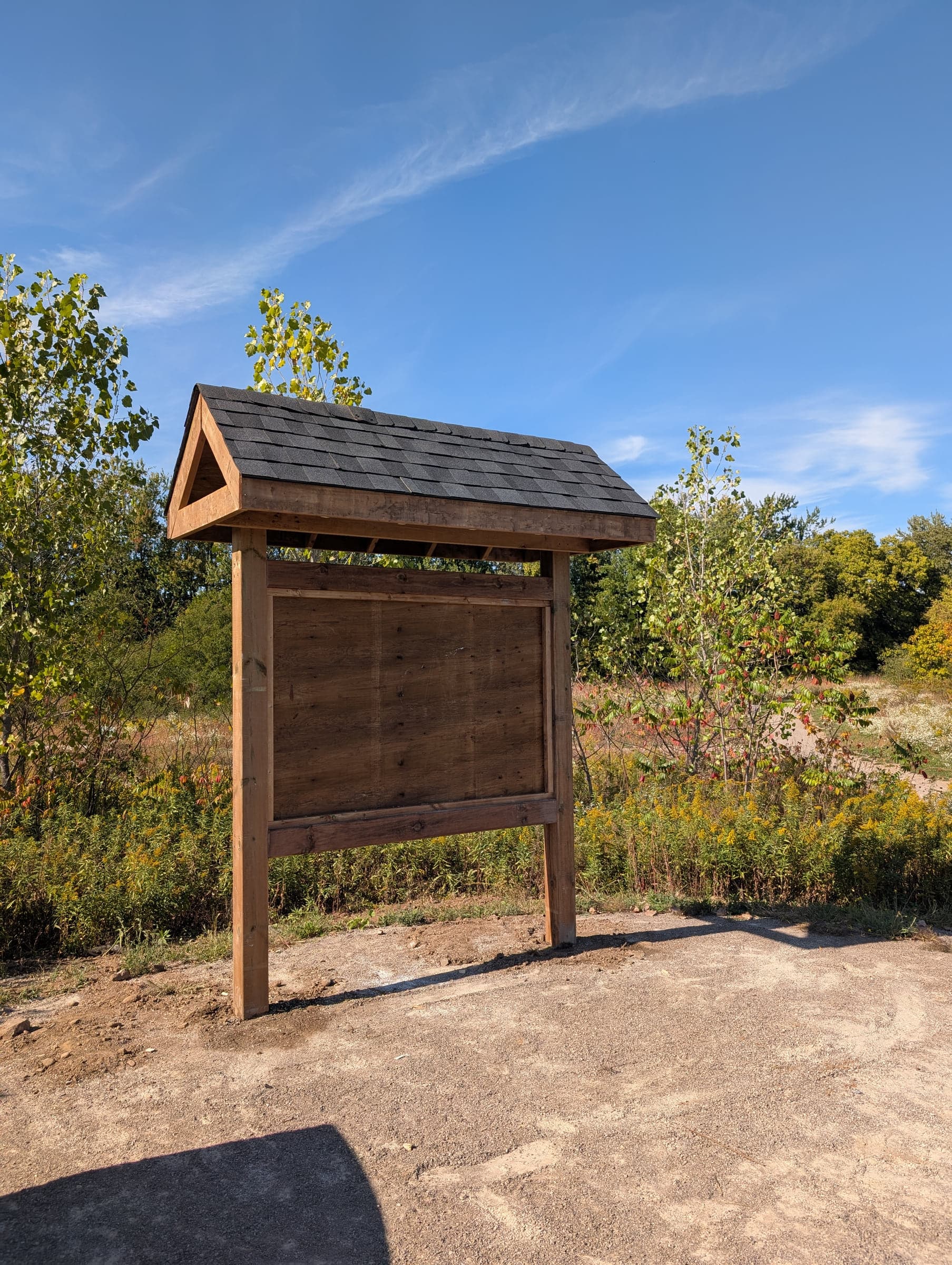 Small finished outdoor kiosk with a dark roof and wood posts