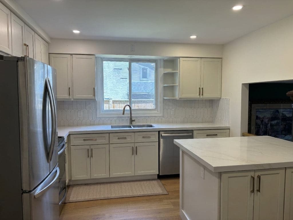 Kitchen after renovation with white cabinetry, light counters, and updated flooring